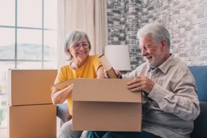 relaxed mature married couple in love resting on couch among paper cardboard boxes