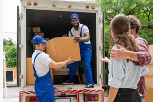 man movers worker in blue uniform unloading cardboard boxes from truck
