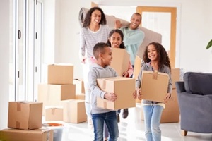 smiling family carrying boxes into new home on moving day
