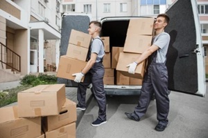 two young handsome smiling workers wearing uniforms are unloading the van full of boxes