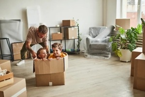 wide angle portrait of two boys playing in big cardboard box while family moving to new house