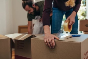 close up of a woman applying adhesive tape on a packing box